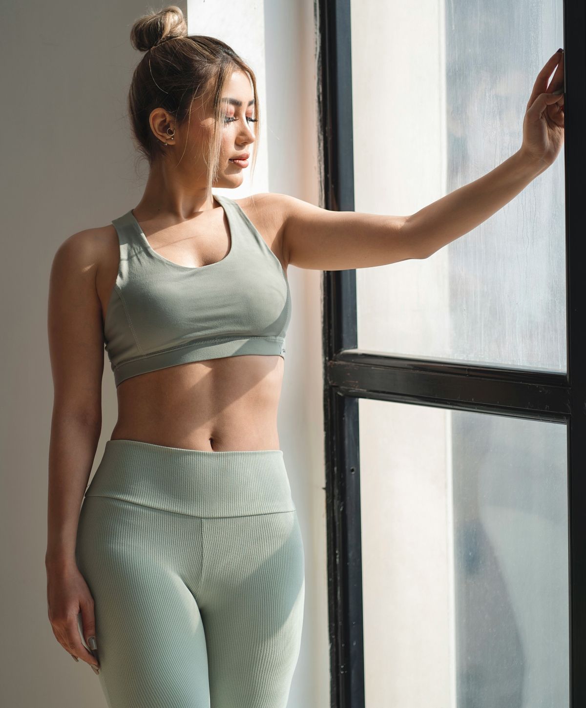 Woman in activewear near a window.
