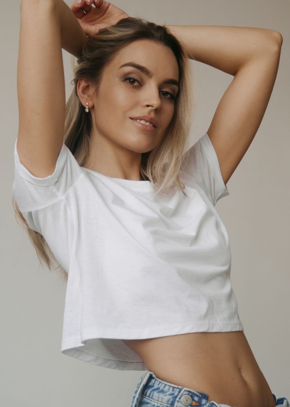 Model posing by window in neutral attire.