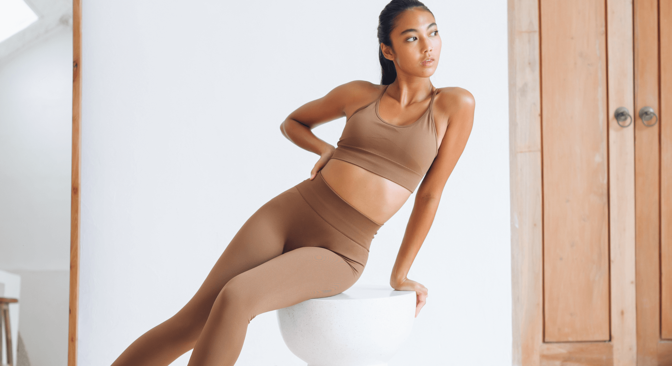 Athletic model posing in neutral-toned activewear.