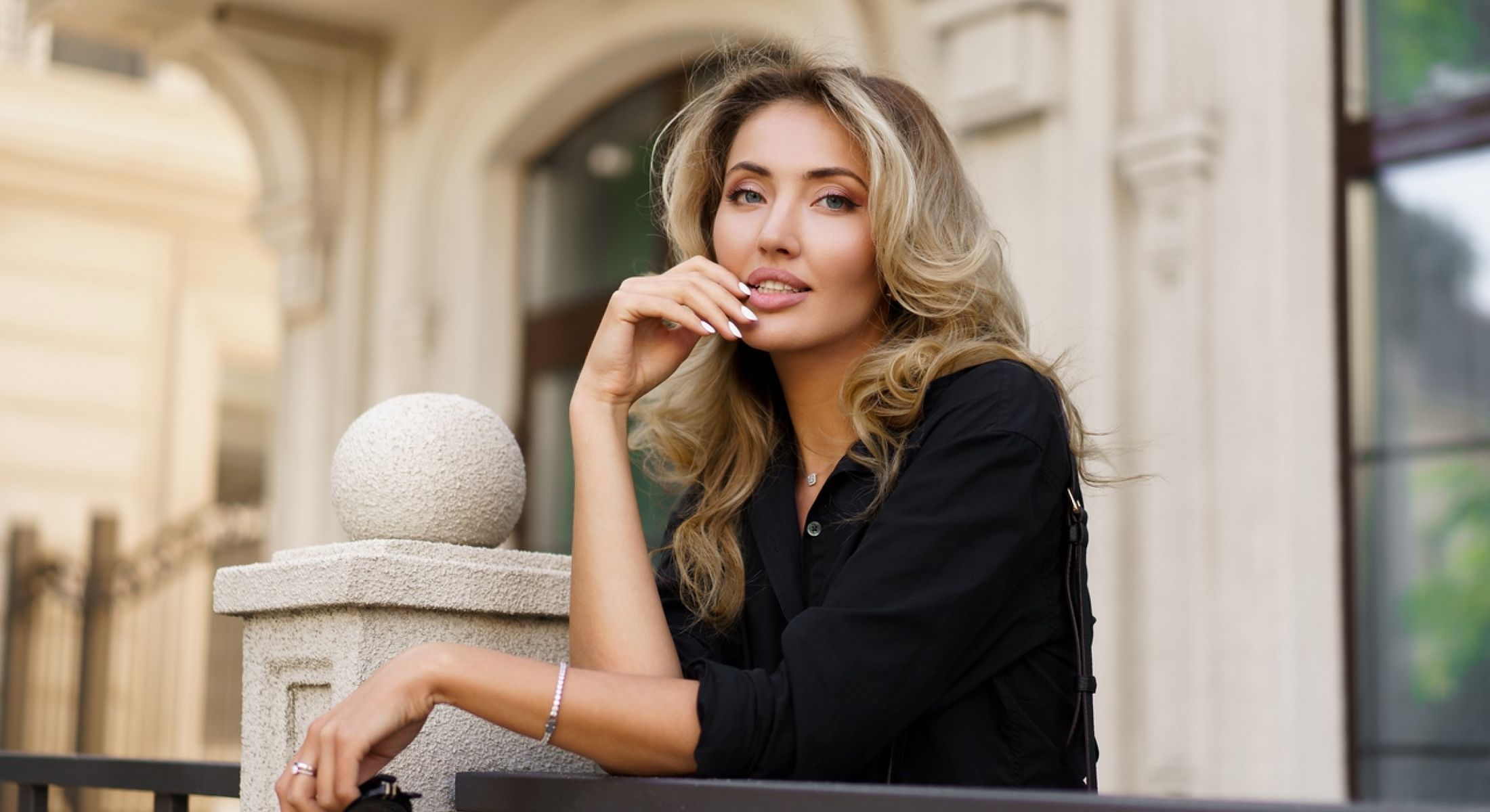 Woman with wavy hair resting on a railing.