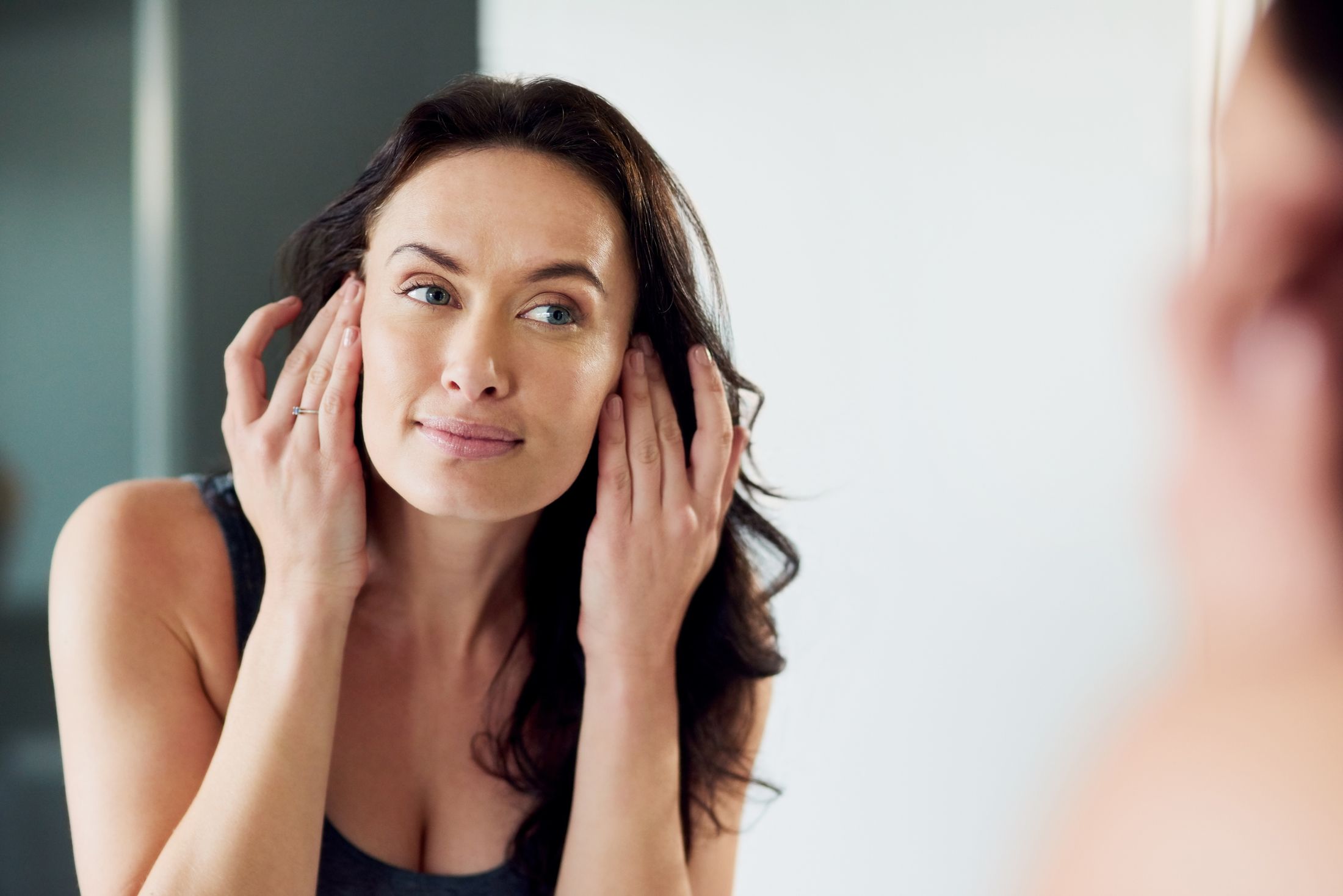 Woman examining her skin in a mirror.
